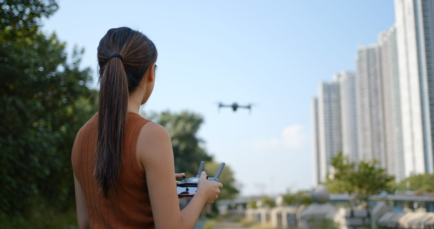 Frau bedient eine Drohne, um eine Luftaufnahme zu filmen.