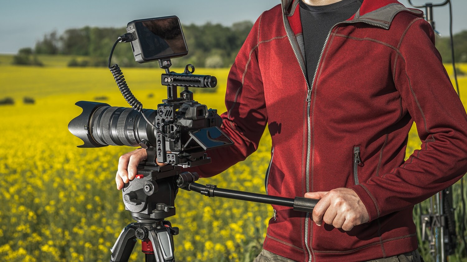 Ein Kameramann auf einem Feld demonstriert eine gute Kameraführung mithilfe eines Stativs.