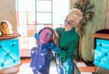 Eine Frau mit Handschuhen modelliert eine violette Puppe mit Perücke.