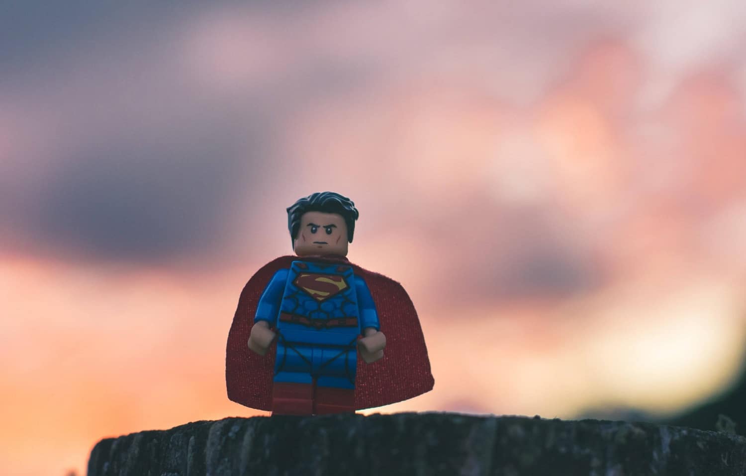 Eine Superman-Legofigur vor einem unscharfen Sonnenuntergang.