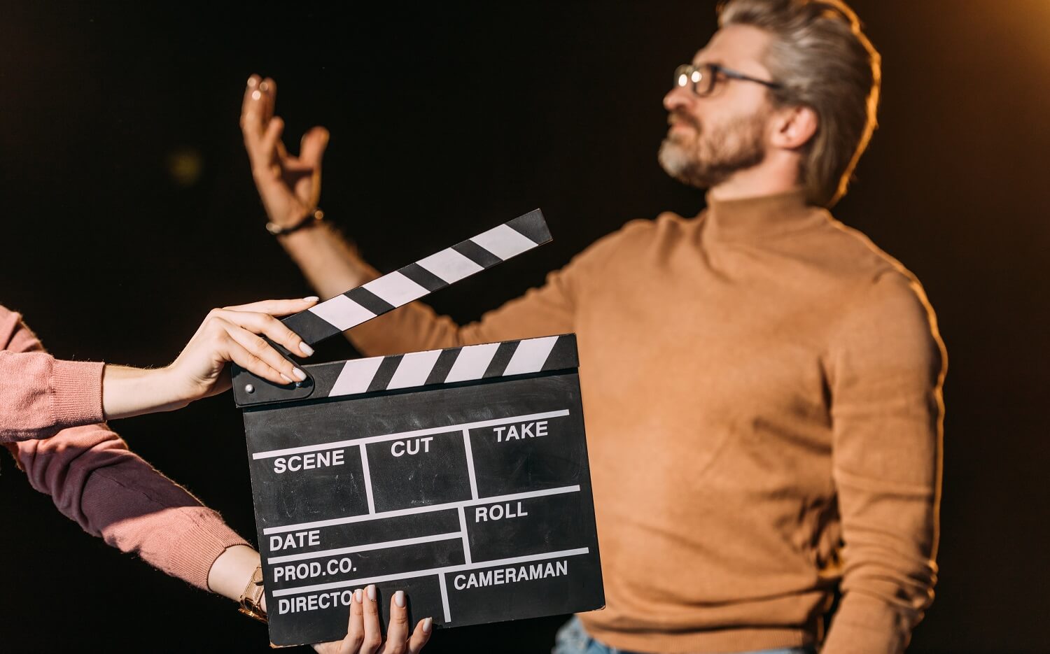 Der Hauptdarsteller eines Films stellt sein Können unter Beweis, während im Vordergrund eine Filmklappe geschlagen wird.