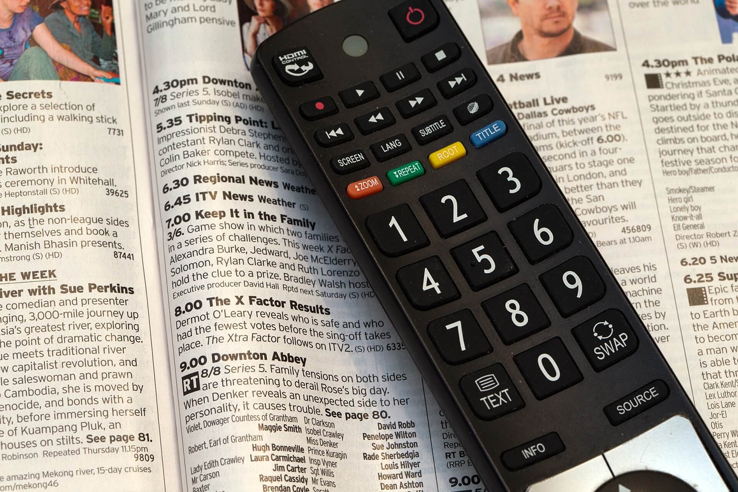 Eine Fernbedienung liegt auf einem TV-Programmheft.